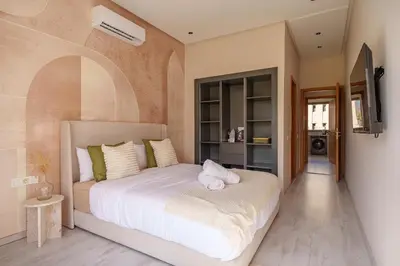 a bedroom with a large white bed in a room at Le Lys - Prestigia Argan - Golf - 6 Prs - Piscine in Marrakech