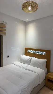 a bedroom with a large white bed and a chandelier at 3 bedroom apartment prestigia jade in Marrakech