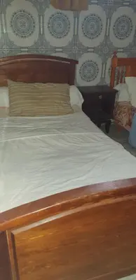 a bed with a wooden headboard and white sheets at Chez Omar in Marrakech