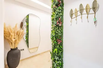 a black vase with plants and a mirror on a wall at Magnifique appartement 2 chambres à Menara Garden Marrakech in Marrakech