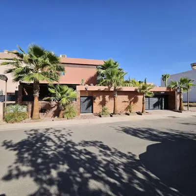 a building with palm trees in front of a street at Magnifique villa spacieuse Route de l'ourika in El Rhechat