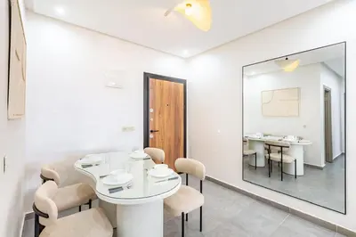 a dining room with a table and chairs and a mirror at Magnifique appartement 2 chambres route du barrage in Marrakech