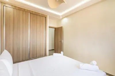 a bedroom with two white beds and a wooden wall at Magnifique appartement 2 chambres route du barrage in Marrakech