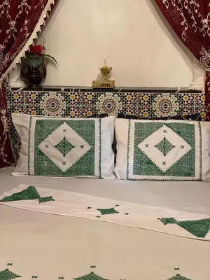 a bed with green and white pillows on it at chez Zaki in Marrakech