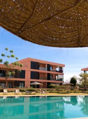 a swimming pool with an umbrella in front of a building at ART NORIA Private garden - pool view in Marrakech