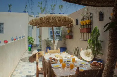 a table with food and a umbrella on a patio at Riad Eljazouli in Marrakech