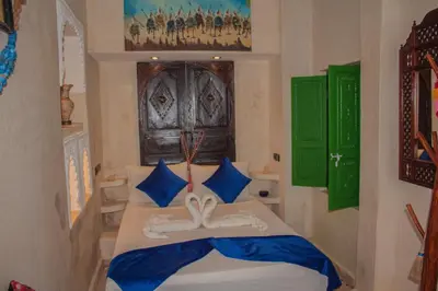a bedroom with a bed with blue and green decorations at Riad Eljazouli in Marrakech