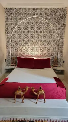 a bedroom with a large bed with red and white sheets at Riad Eljazouli in Marrakech