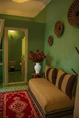 a bedroom with a bed and a vase of red flowers at Riad Eljazouli in Marrakech