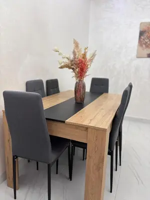 a wooden table with chairs and a vase with flowers at Your Host in Marrakech