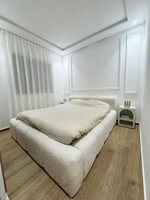 a white bedroom with a bed and a wooden floor at Appartement de Luxe 3 Chambres avec piscine au centre in Marrakech