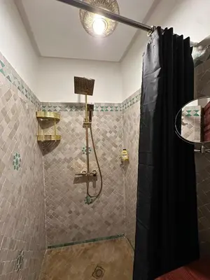 a shower with a black shower curtain in a bathroom at Riad Talal in Marrakech