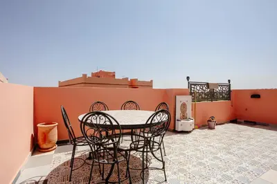 a patio with a table and chairs on a roof at Séjour confort jacuzzi et terrasse à Targa in Marrakech