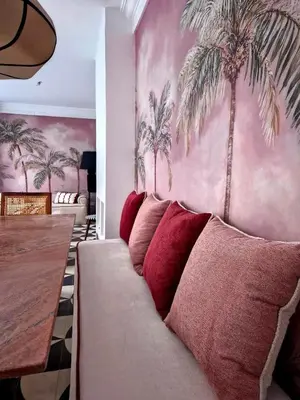a living room with a couch with palm trees on the wall at Riad Beltza - 