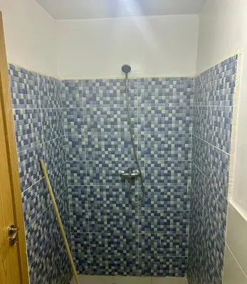 a bathroom with a shower with blue tiles on the wall at Residence Jnane Tissir Marrakech in Marrakech