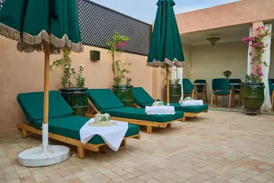 a group of green chairs and umbrellas on a patio at Riad Lia ou Lik in Marrakech