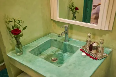 a bathroom sink with a vase of flowers and a mirror at Riad Lia ou Lik in Marrakech