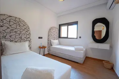 a bedroom with a white bed and a couch at Gueliz Central Apartment with Pool and Parking in Marrakech
