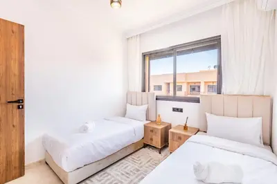 two beds in a room with a window at Pool views 2BR family apartment in Marrakech