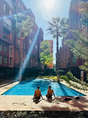 two men sitting in a swimming pool in a city at Chic & Comfort, Experience Marrakech differently in Marrakech