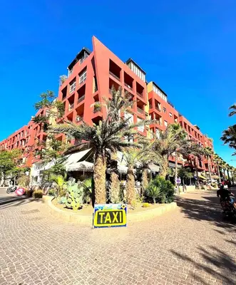 a large red building with a taxi sign in front of it at Chic & Comfort, Experience Marrakech differently in Marrakech