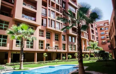 an apartment building with a swimming pool and palm trees at Chic & Comfort, Experience Marrakech differently in Marrakech