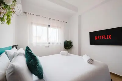a white bedroom with a white bed and green pillows at 4BR Duplex - Jacuzzi - 10 min walk to M Avenue with Parking and Pool in Marrakech