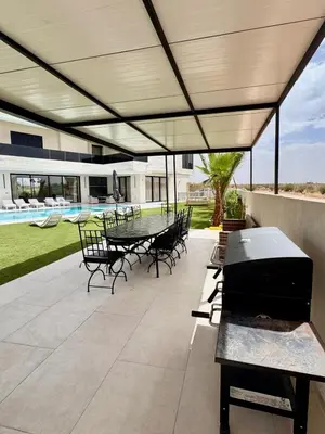 a patio with a table and chairs and a grill at Villa Prestige Zakarya - GOLF AKENZA2 MARRAKECH in Marrakech