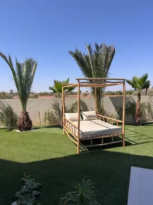 a swing bed on a lawn with palm trees at Villa Prestige Zakarya - GOLF AKENZA2 MARRAKECH in Marrakech