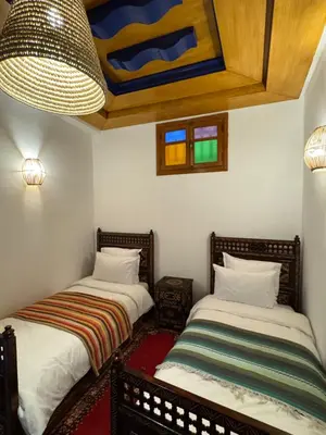 two beds in a small room with a ceiling at Riad Zahri 18 in Marrakech
