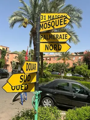 a pole with street signs in front of a car at Dar Azélia - Charming riad with terrace & pool near Medina in Marrakech