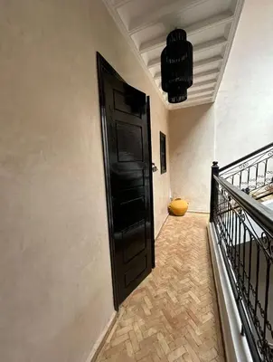 a hallway with a black door and a staircase at Dar Azélia - Charming riad with terrace & pool near Medina in Marrakech