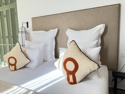 a bed with white pillows with a headboard at Riad 29 Mouassine in Marrakech