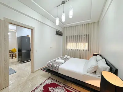 a bedroom with a large bed and a table at Cocon à Marrakech avec balcon in Marrakech