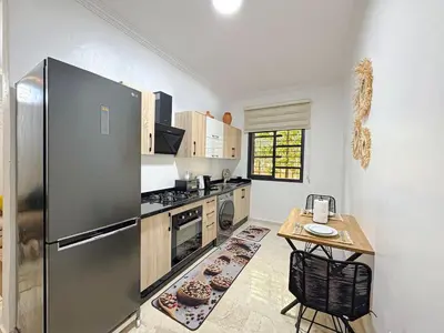 a kitchen with a stainless steel refrigerator and a table at Cocon à Marrakech avec balcon in Marrakech