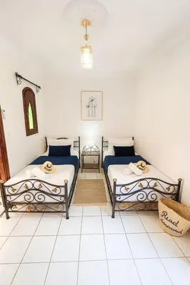 two beds in a room with white tile floors at Riad Mounad with pool - close to Jemaa el-fna in Marrakech