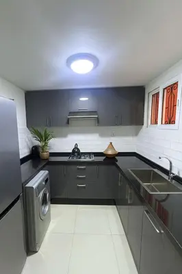 a kitchen with black cabinets and a sink and a dishwasher at Riad Mounad with pool - close to Jemaa el-fna in Marrakech