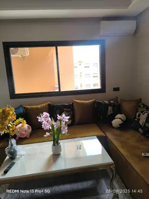 a living room with a couch and a table with flowers at Appartement moderne au cœur de Marrakech in Marrakech
