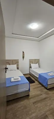 two twin beds in a room with wooden floors at Appartement moderne à louer Marrakech in Marrakech