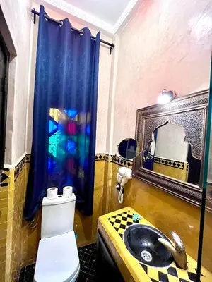 a bathroom with a sink and a toilet and a mirror at Hotel Jannat in Marrakech