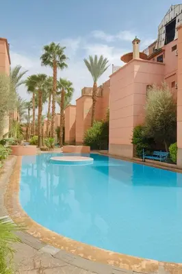 a large blue swimming pool with palm trees at Studio mezzanine cosy près de Jemaa el-Fna in Marrakech