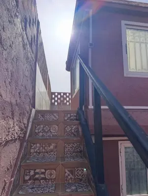 a stairway leading up to a building with the sun shining at Riad kech residence al Qarya syahiya Marrakech in Marrakech