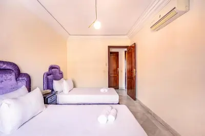 two beds in a room with purple furniture at Cosy Appartement Rue Loubnane in Marrakech