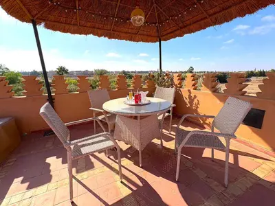 a table and chairs on a patio with an umbrella at Palais Khemia in Marrakech