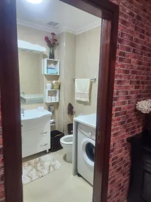 a bathroom with a washing machine and a brick wall at Appartement in Marrakech