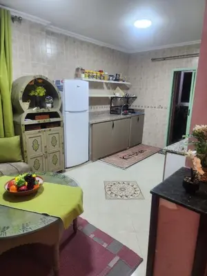 a kitchen with a refrigerator and a table with a bowl of fruit at Appartement in Marrakech