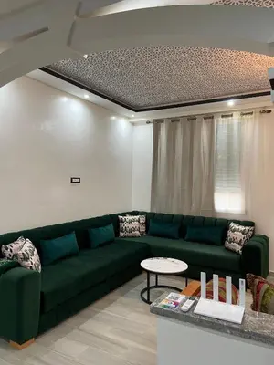 a living room with a green couch and a table at KSYI IMMO 6 Marrakech Aéroport in Marrakech