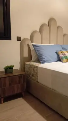 a bedroom with a bed with a headboard and a table at Charmant appartement au coeur de Guéliz à côté de train in Marrakech