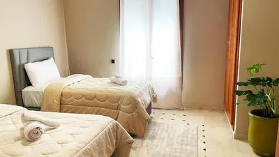 a bedroom with two beds and a potted plant at Chic Plaza City Center in Marrakech