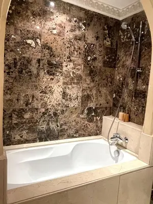 a bath tub in a bathroom with a stone wall at Chic Plaza City Center in Marrakech